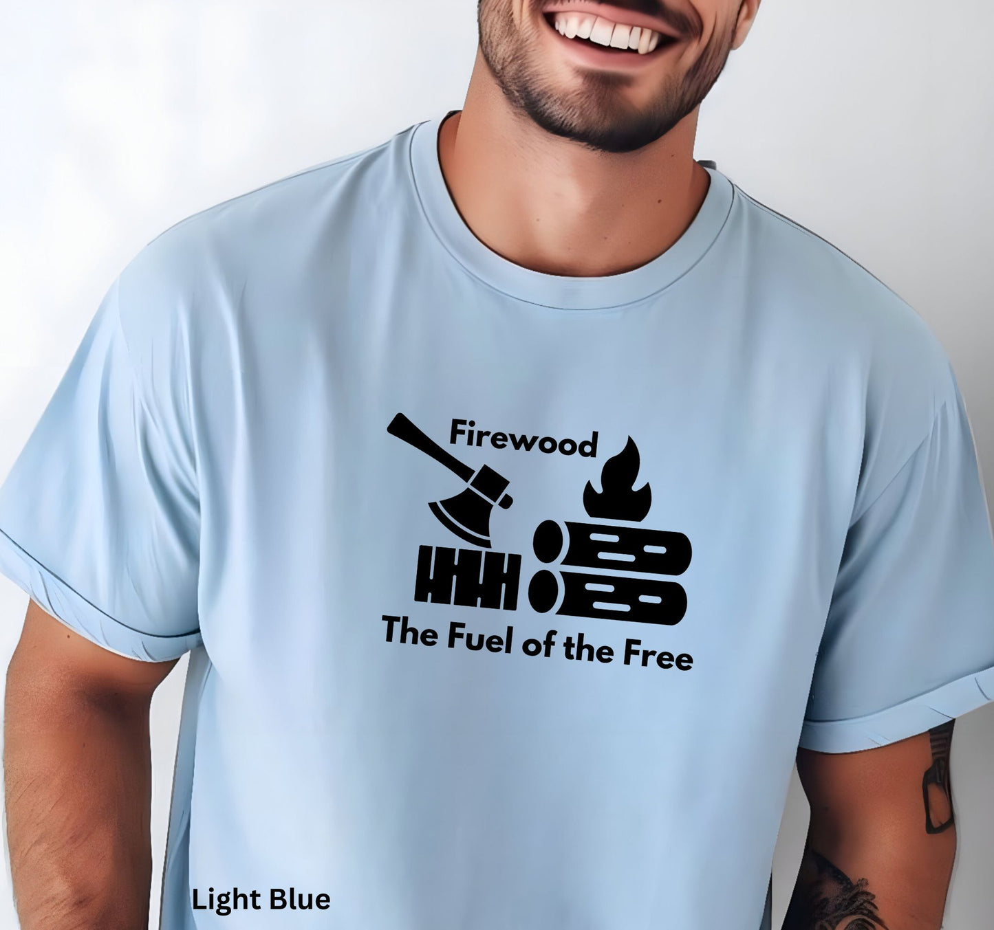 Light Blue T-shirt with the phrase 'Firewood: The Fuel of the Free,' featuring a campfire, stacked firewood, and an ax—perfect for wood heat lovers and homesteaders.