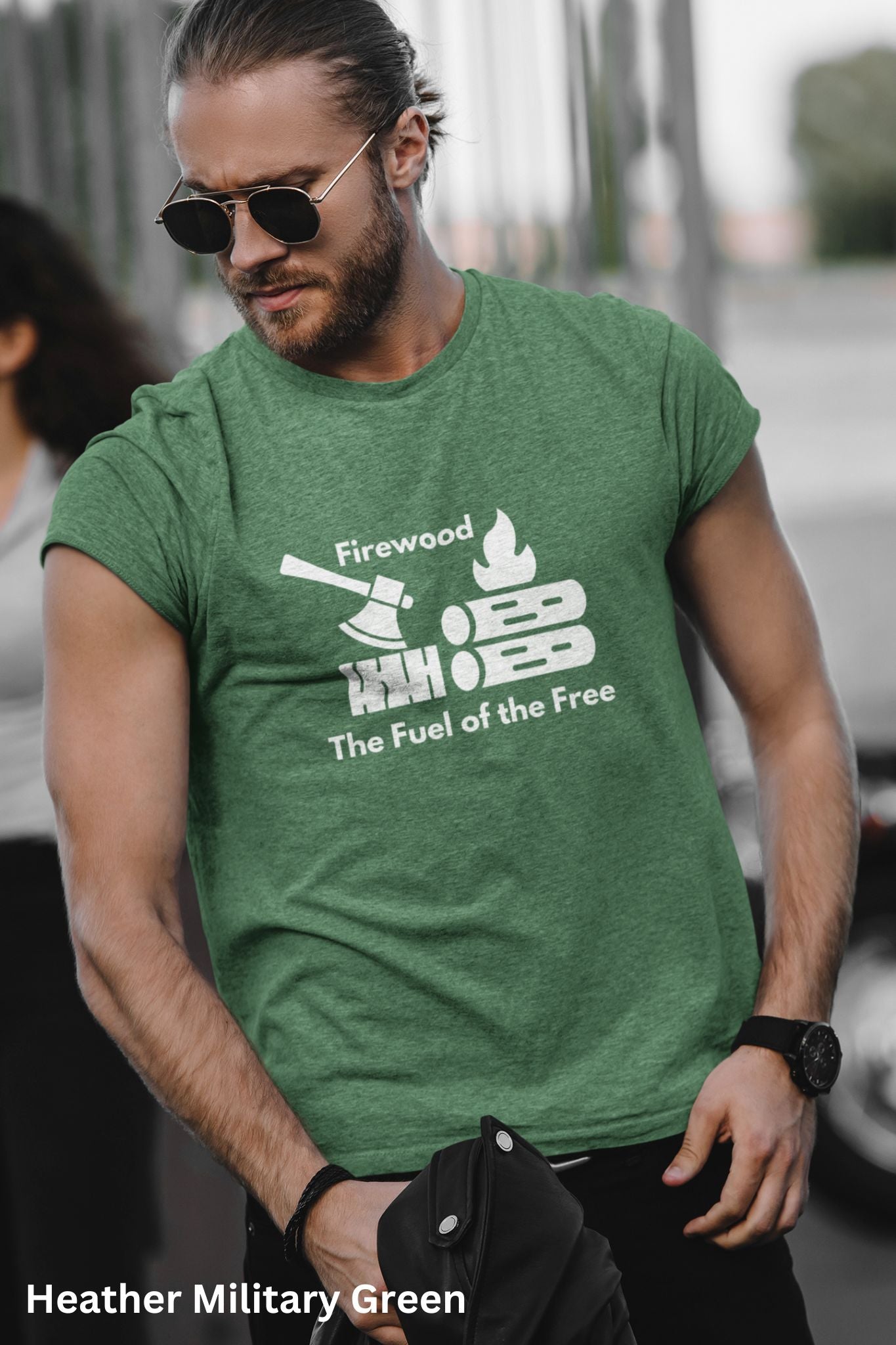 Military Green T-shirt with the phrase 'Firewood: The Fuel of the Free,' featuring a campfire, stacked firewood, and an ax—perfect for wood heat lovers and homesteaders.