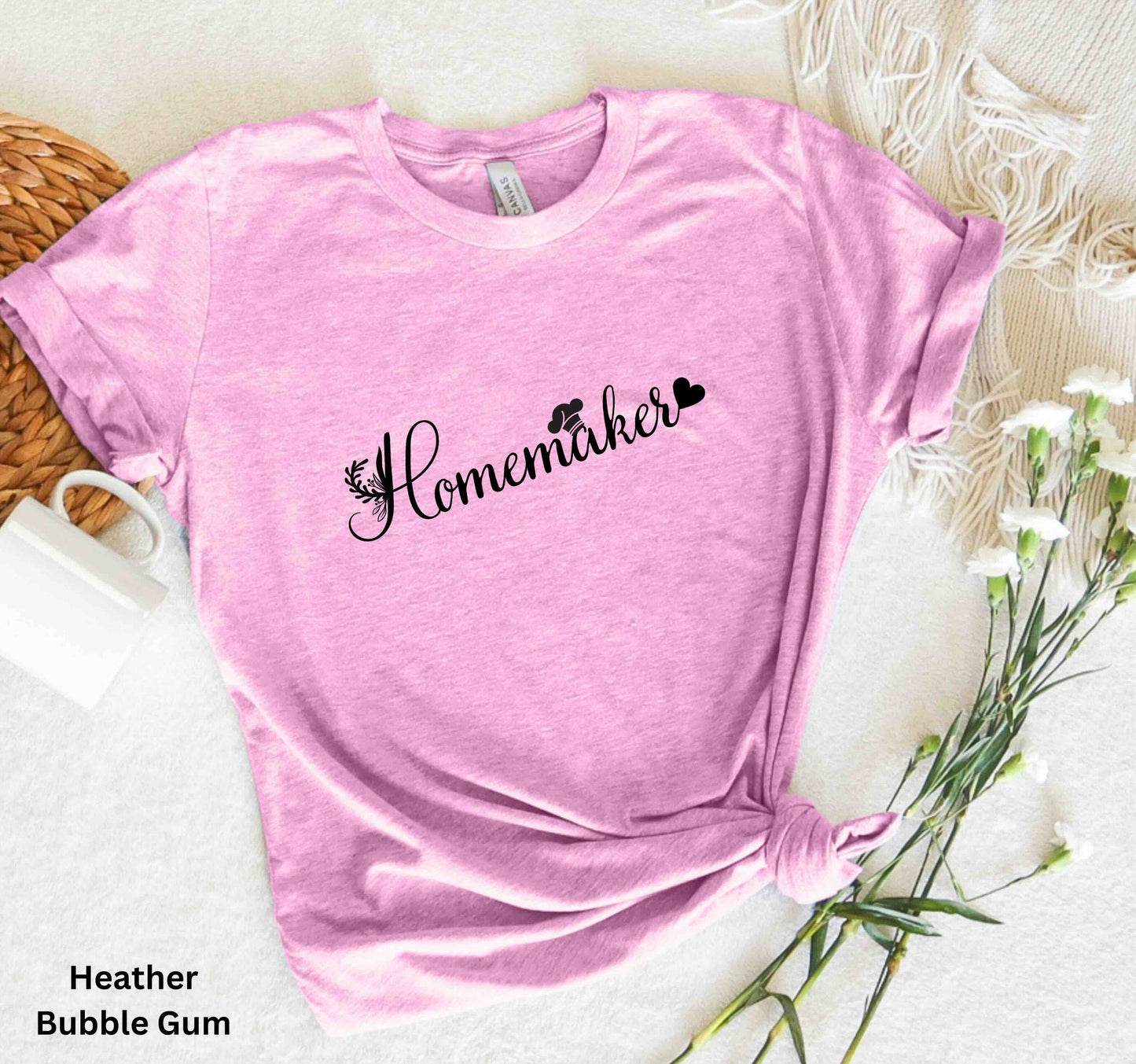 Light pink homemaker t-shirt with floral design, chef’s hat over the 'A,' and heart accent, perfect for homesteaders, homebakers, and simple living enthusiasts.