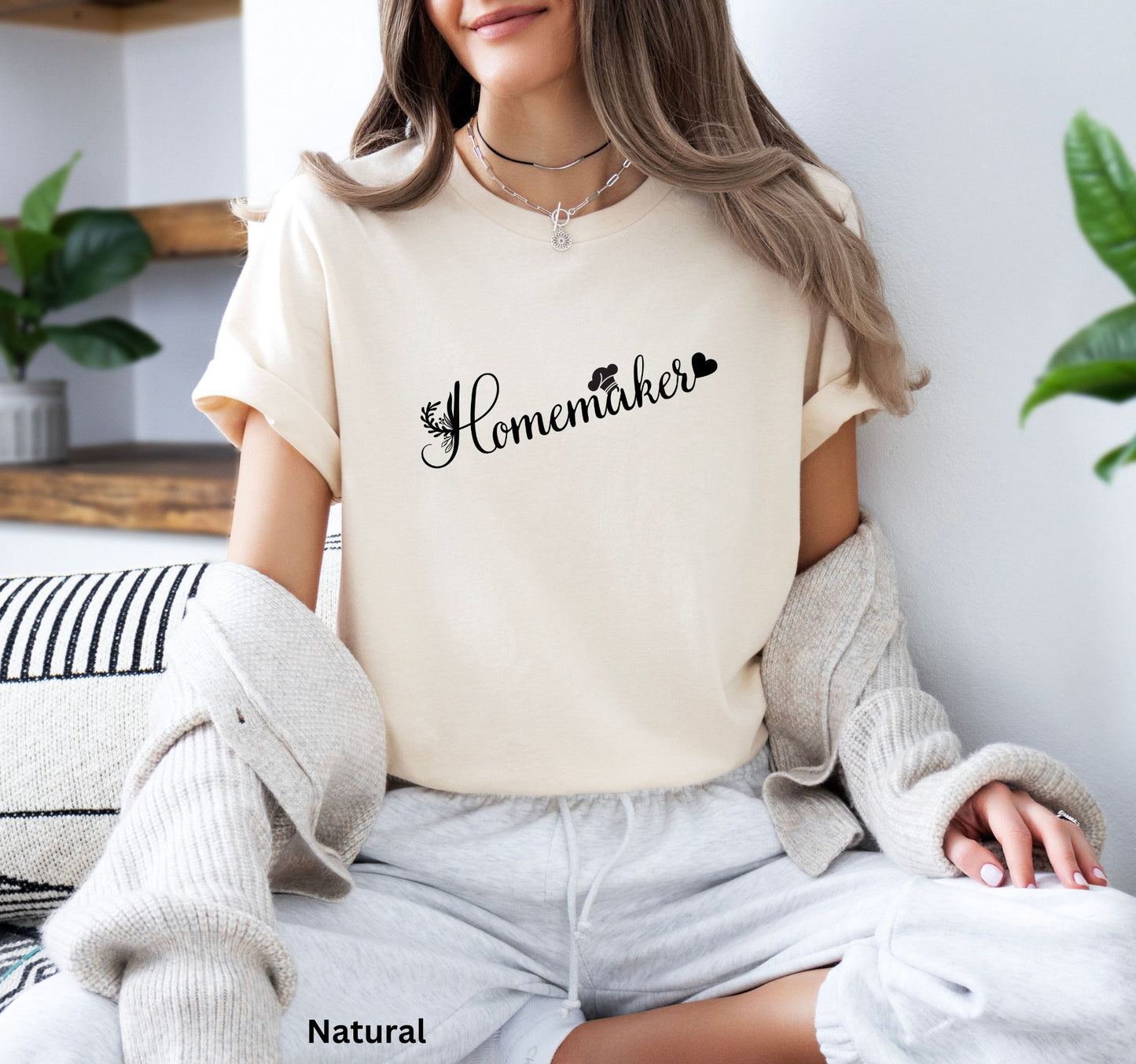 Homemaker t-shirt in natural color with floral design, chef’s hat over the 'A,' and heart accent, perfect for homesteaders, homebakers, and simple living enthusiasts.