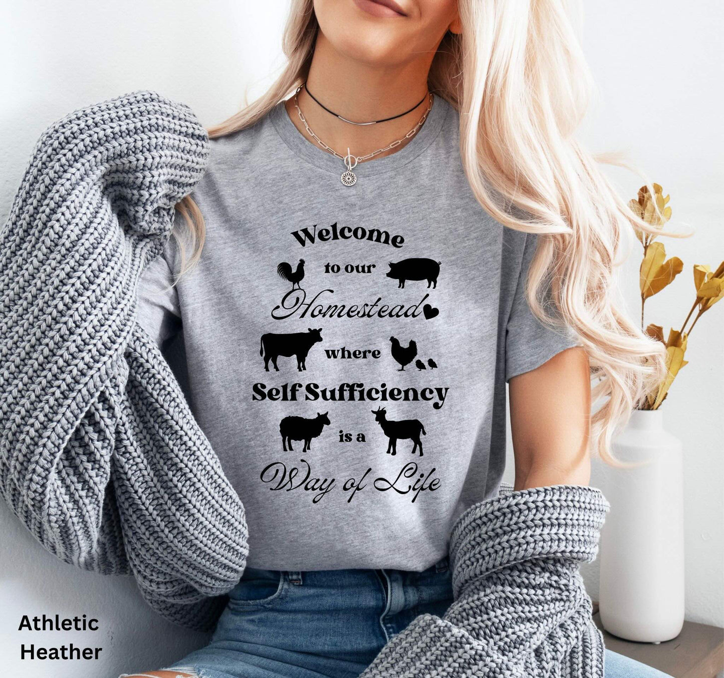 Light Grey Homestead t-shirt featuring the phrase 'Welcome to our Homestead where Self-Sufficiency is a Way of Life' with farm animals including a rooster, hen with chicks, pig, cow, sheep, and goat. Perfect for homesteaders and farm life lovers.