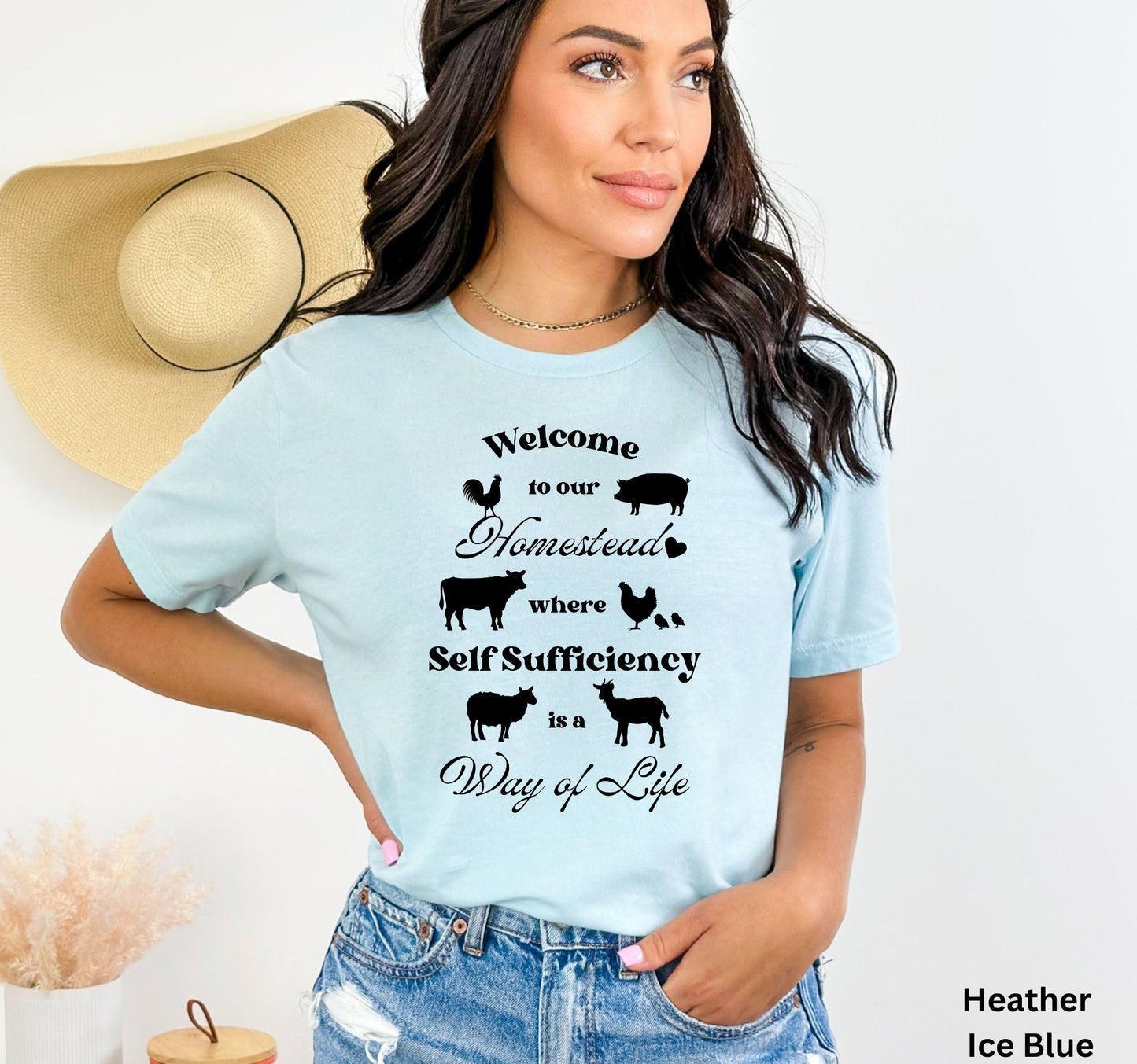 Light Blue Homestead t-shirt featuring the phrase 'Welcome to our Homestead where Self-Sufficiency is a Way of Life' with farm animals including a rooster, hen with chicks, pig, cow, sheep, and goat. Perfect for homesteaders and farm life lovers.
