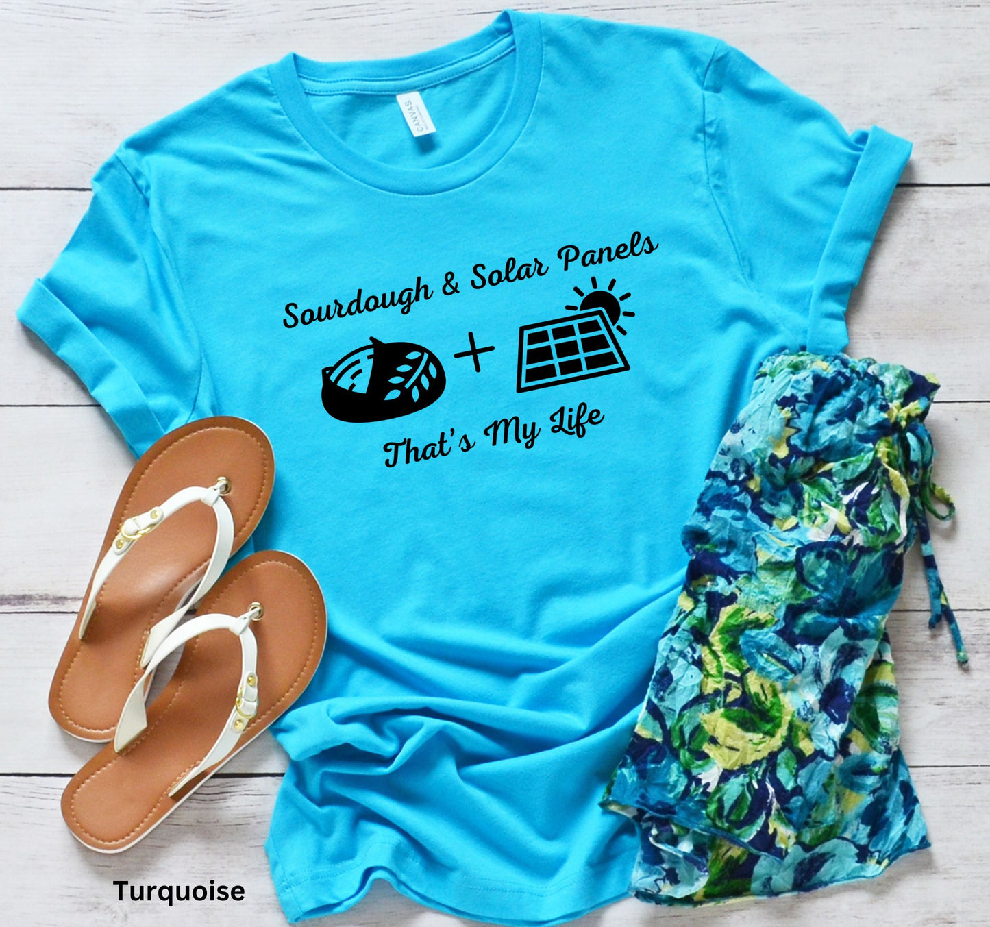 Turquoise T-shirt with the phrase 'Sourdough & Solar Panels, That’s My Life,' featuring a loaf of sourdough bread, a solar panel, and the sun—perfect for off-grid living.
