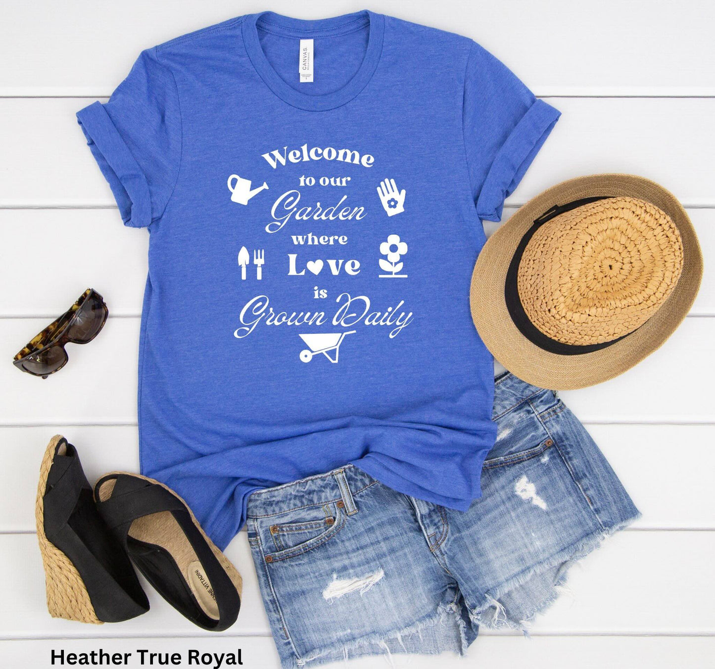 Royal Blue T-shirt with the phrase 'Welcome to our Garden where love is grown daily,' featuring gardening tools, a heart, a wheelbarrow, a flower, gloves, and a watering jug.