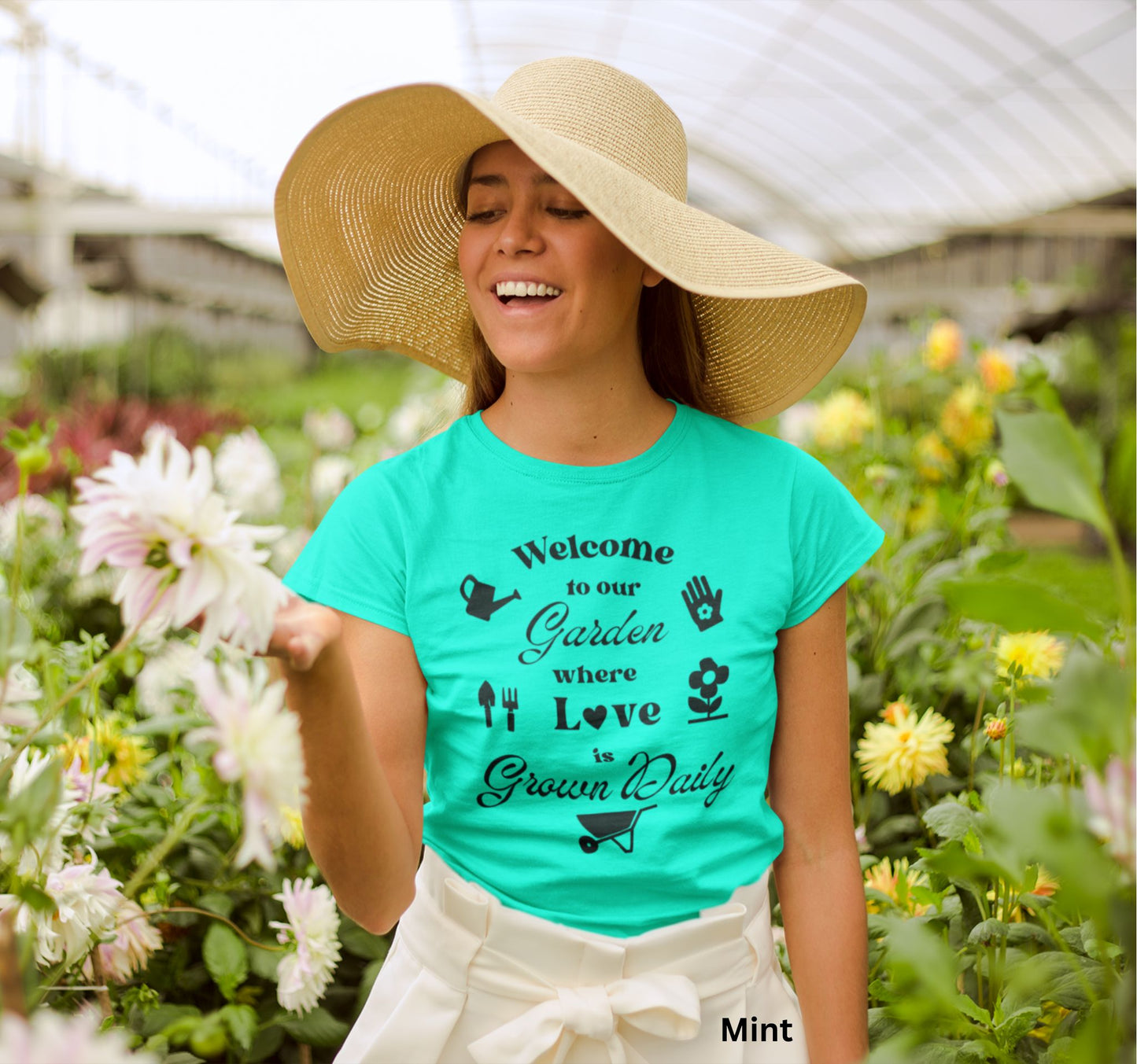 Mint colored t-shirt with the phrase 'Welcome to our Garden where love is grown daily,' featuring gardening tools, a heart, a wheelbarrow, a flower, gloves, and a watering jug.