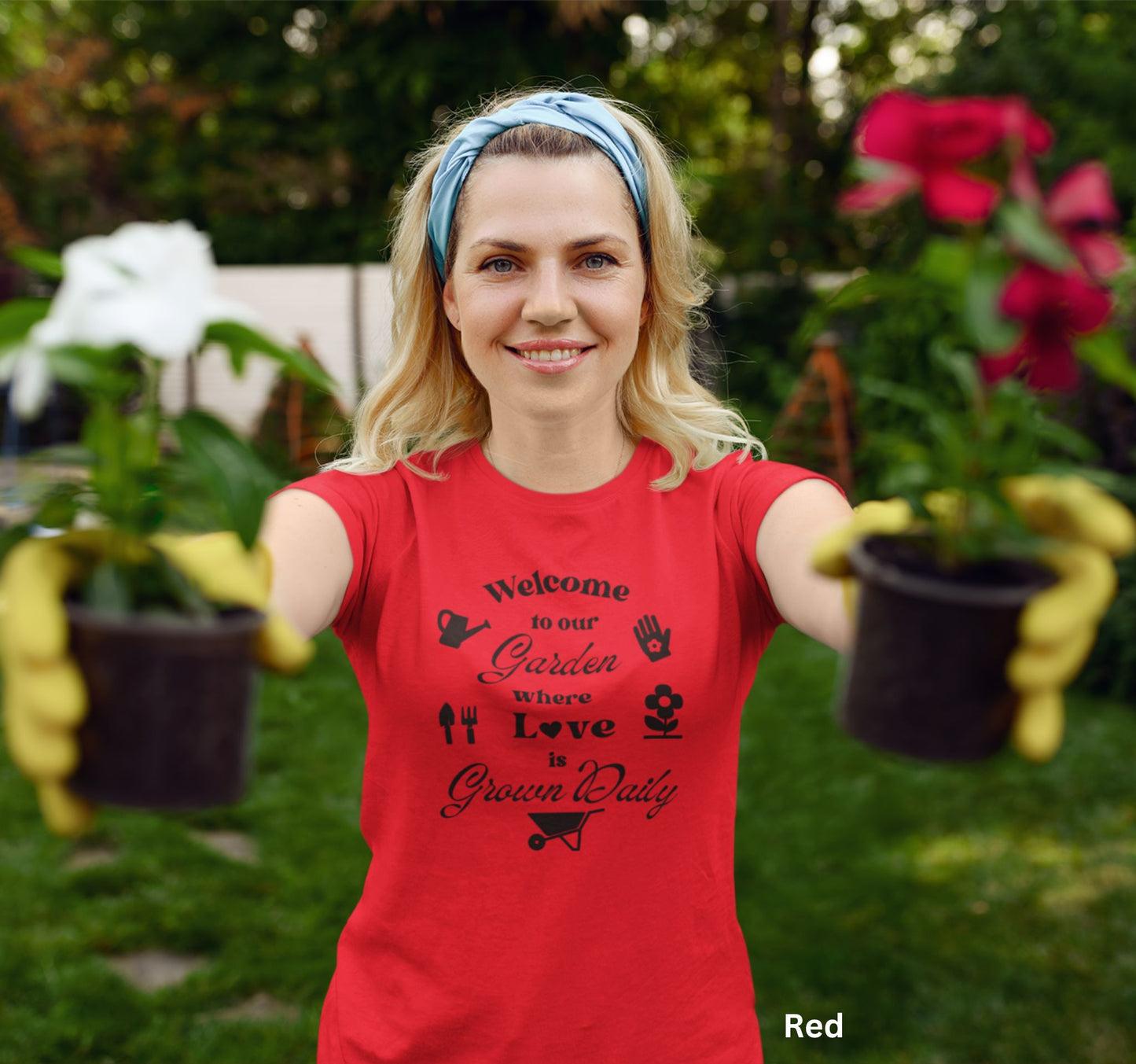 Red T-shirt with the phrase 'Welcome to our Garden where love is grown daily,' featuring gardening tools, a heart, a wheelbarrow, a flower, gloves, and a watering jug.