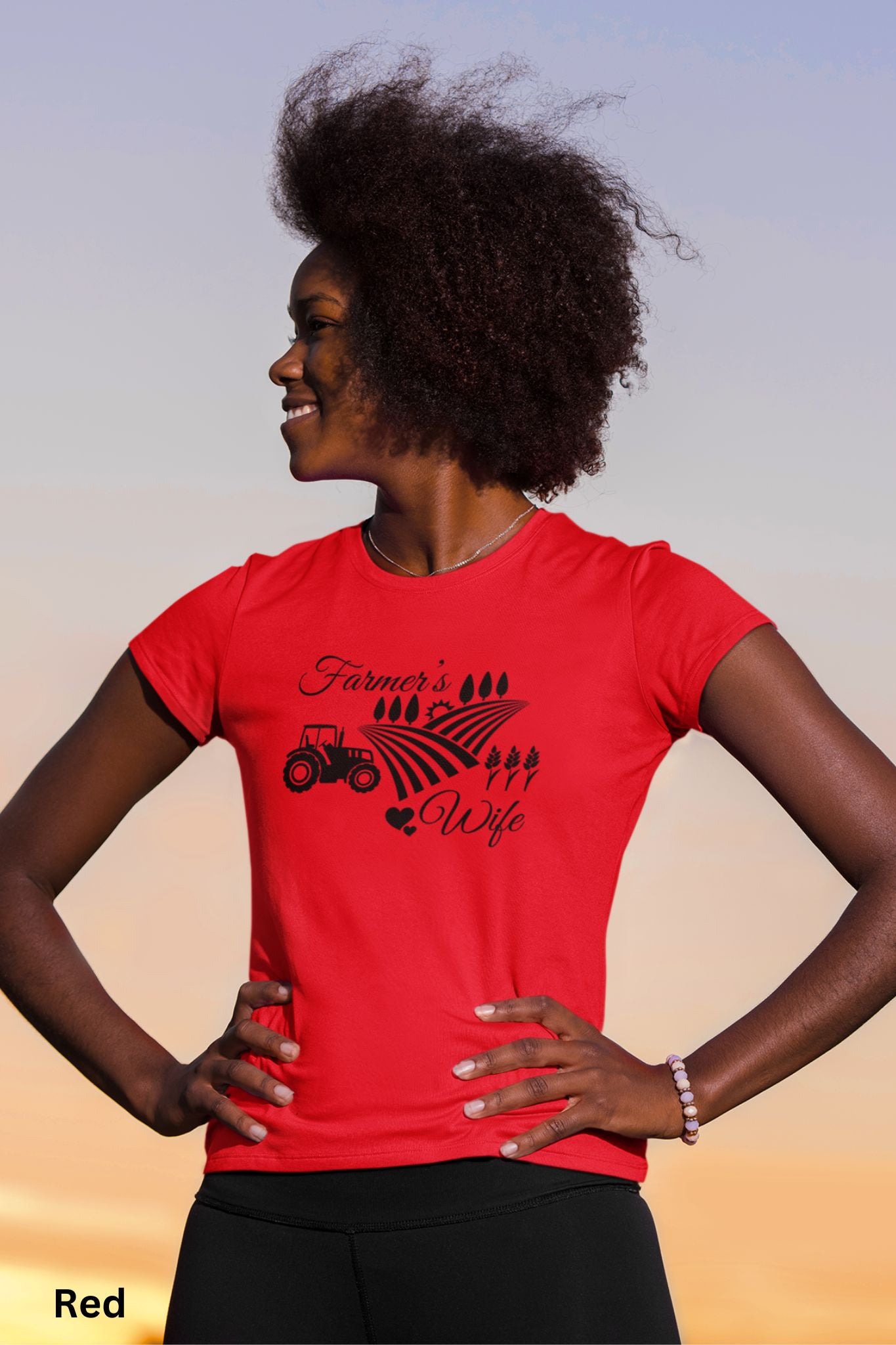 Farmer’s Wife red t-shirt with tractor, wheat field and heart design, celebrating country living and hardworking farm women.